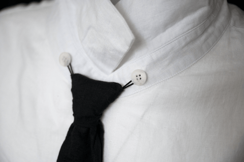 Close-up of a hand-tied detail on a white HACOY linen shirt, the craft of the workshop.